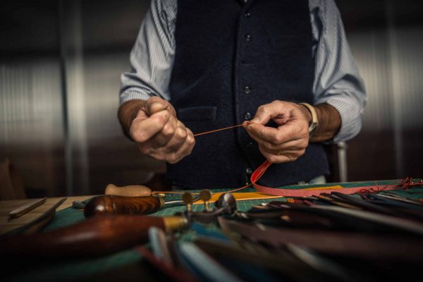 Close up shoot of an artisan working with leather in his laboratory.